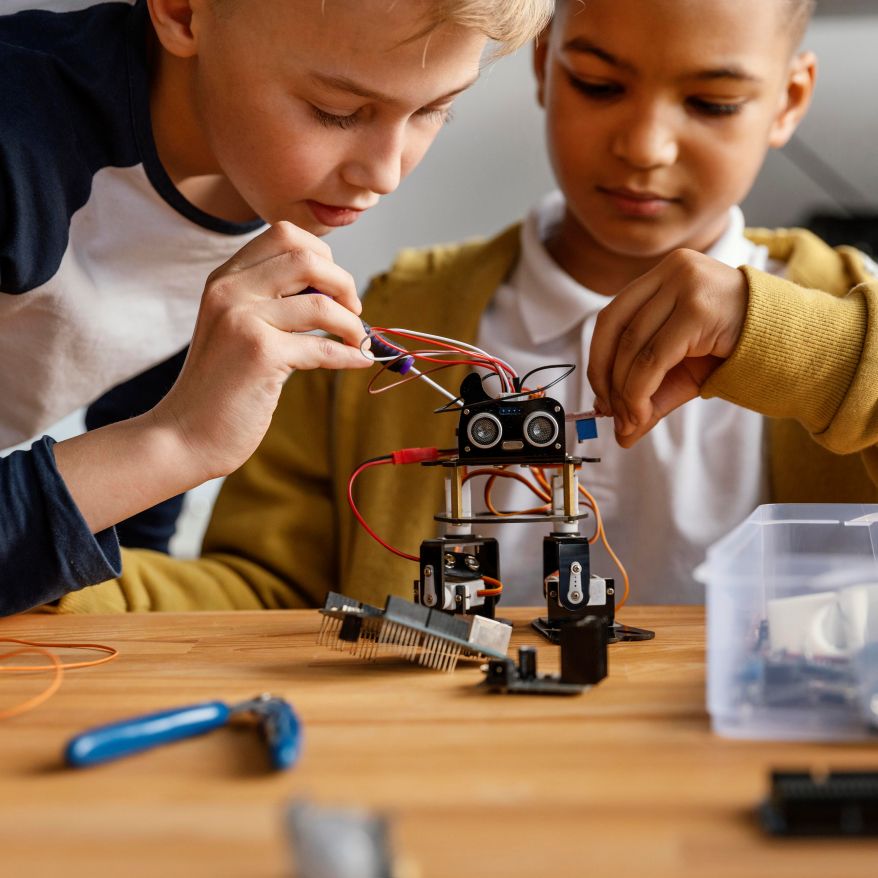students collaborating on assembling and wiring a small robotics device, demonstrating hands-on learning in STEM education.